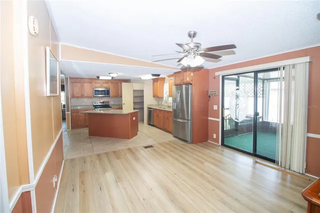 a kitchen with stainless steel appliances kitchen island granite countertop a refrigerator a stove and a wooden floors