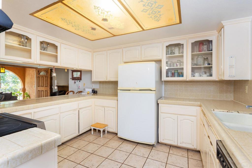 436 Mason Road Vista, CA 92084 - Photo 10 of 32 a kitchen with a refrigerator a sink dishwasher and white cabinets next to a window