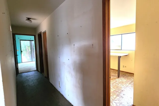 a view of a hallway with wooden floor and a bathroom