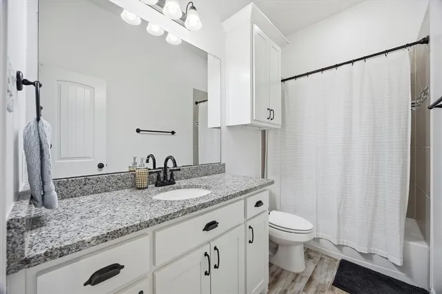 a bathroom with a granite countertop sink a toilet and a mirror