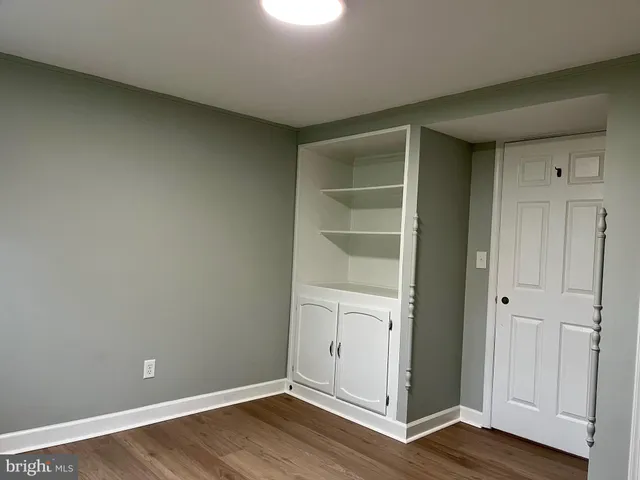 a view of an empty room with wooden floor and closet
