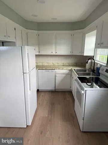 a kitchen with stainless steel appliances granite countertop a refrigerator a sink and white cabinets