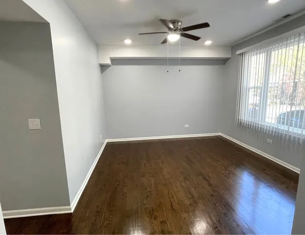 an empty room with wooden floor fan and windows