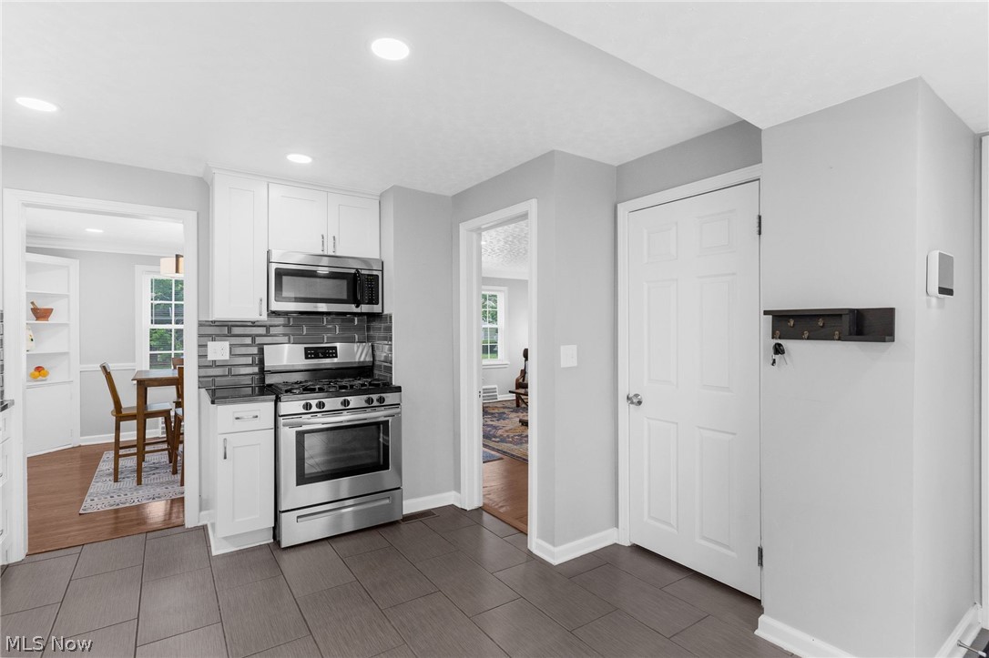 3625 Ludgate Road Cleveland, OH 44120 - Photo 5 of 16 Kitchen with dark tile flooring, backsplash, white cabinetry, and appliances with stainless steel finishes