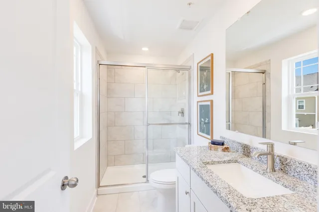 a bathroom with a granite countertop sink a mirror and a shower