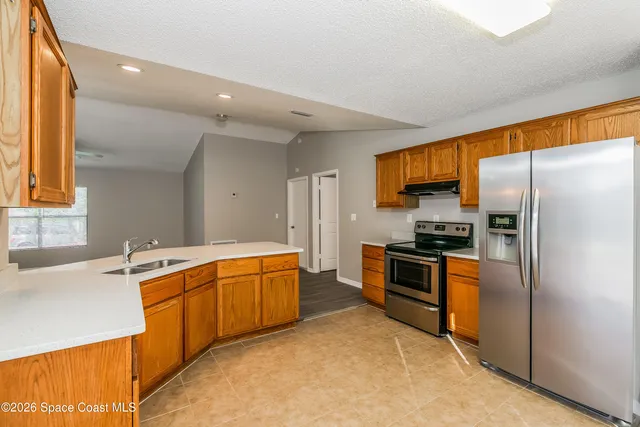 a large kitchen with stainless steel appliances granite countertop a stove refrigerator and a sink