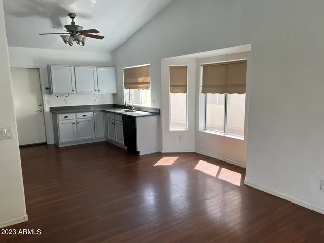 a kitchen with stainless steel appliances granite countertop a stove a sink and white cabinets with wooden floor next to windows