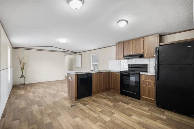 a kitchen with granite countertop a refrigerator and a stove top oven