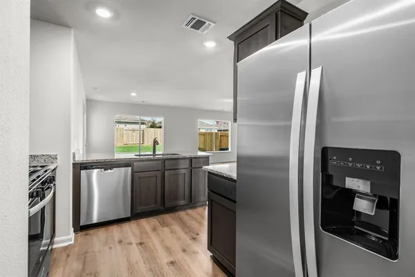 a kitchen with stainless steel appliances granite countertop a refrigerator a stove and a sink