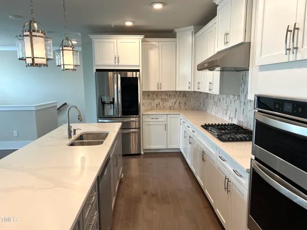 a kitchen with stainless steel appliances granite countertop a sink a stove and a refrigerator