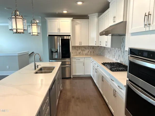 a kitchen with stainless steel appliances granite countertop a sink a stove and a refrigerator