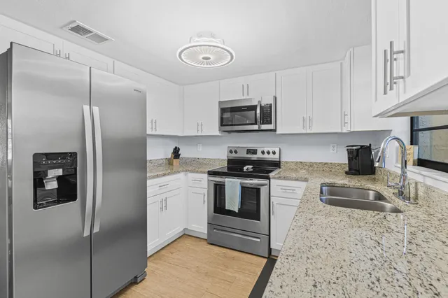 a kitchen with stainless steel appliances granite countertop a refrigerator sink and stove