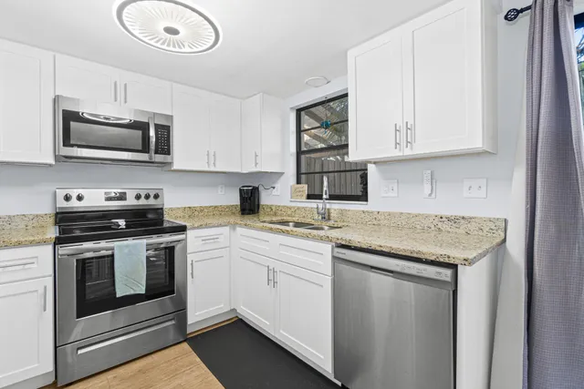 a kitchen with stainless steel appliances granite countertop a sink a stove a microwave and wooden cabinets