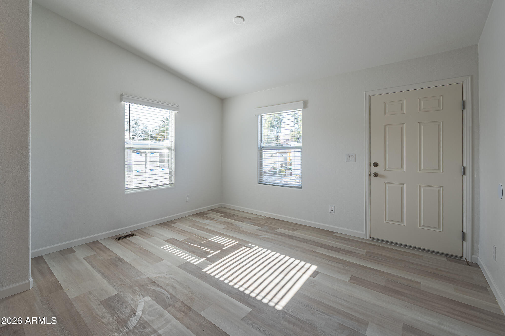 1250 East Bell Road, Unit 11 Phoenix, AZ 85022 - Photo 13 of 24 a view of an empty room with wooden floor and a window