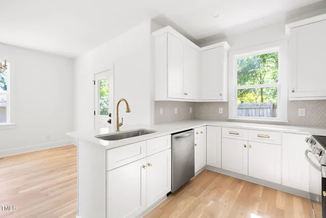 a kitchen with white cabinets appliances and a window