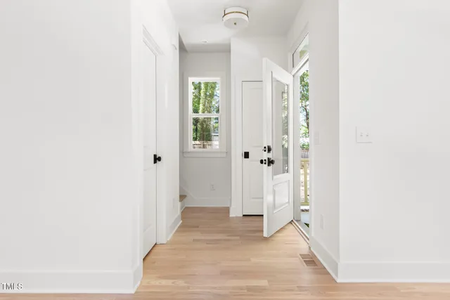 a view of a hallway with wooden floor and a bathroom