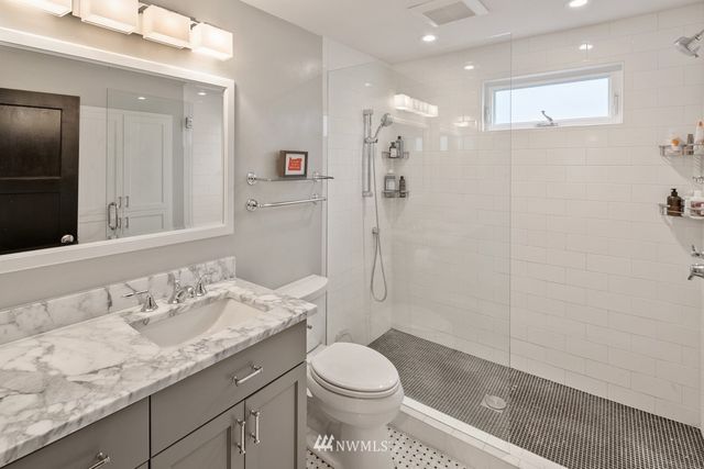 a bathroom with a granite countertop sink a toilet and shower