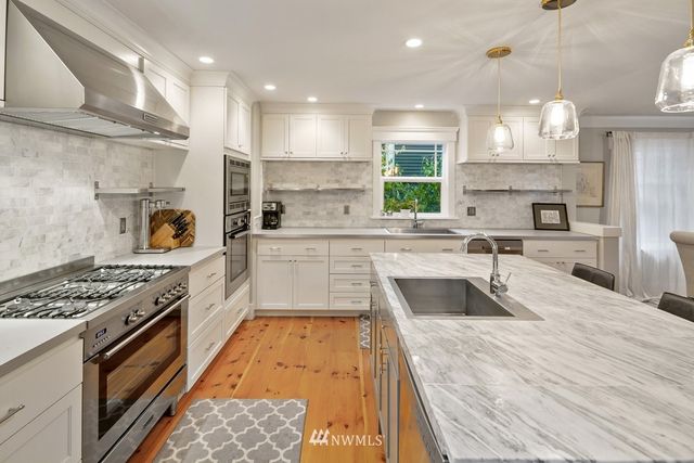 a large kitchen with stainless steel appliances granite countertop a sink stove and a refrigerator