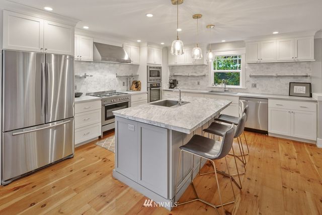 a kitchen with granite countertop a table chairs stainless steel appliances and cabinets