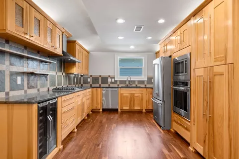 a large kitchen with stainless steel appliances granite countertop a large counter top and a wooden floors