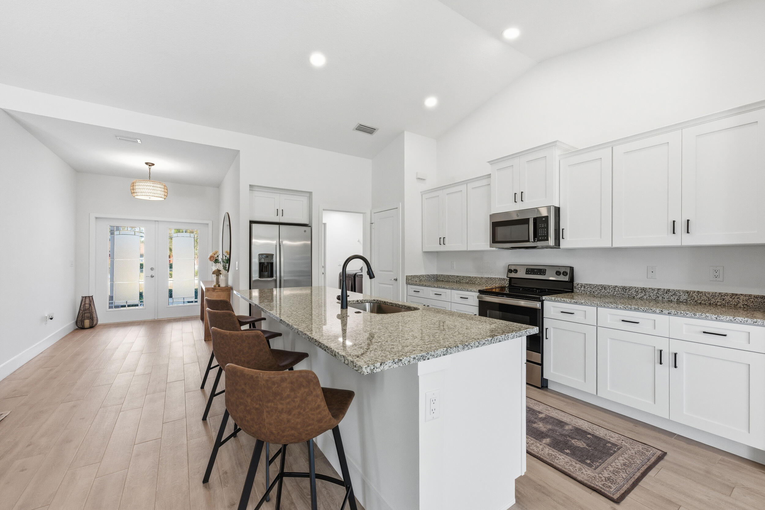 18932 42nd Road North The Acreage, FL 33470 - Photo 18 of 45 a kitchen with stainless steel appliances granite countertop a stove top oven a sink a refrigerator and white cabinets with wooden floor