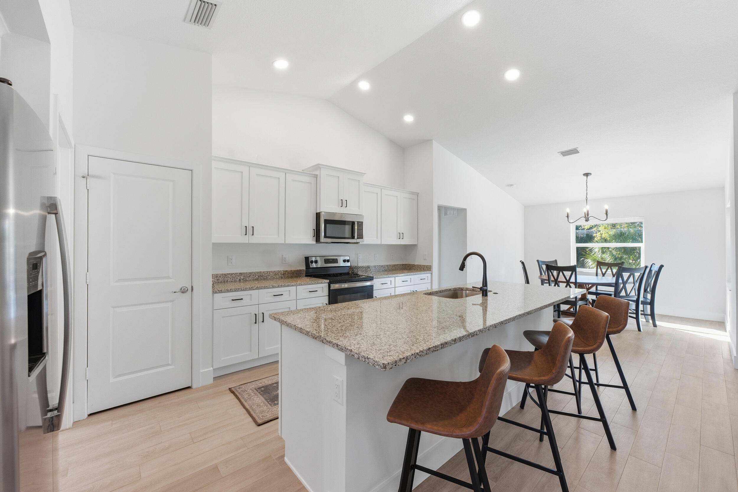 18932 42nd Road North The Acreage, FL 33470 - Photo 20 of 45 a large kitchen with stainless steel appliances granite countertop a stove a sink a refrigerator and white cabinets with wooden floor