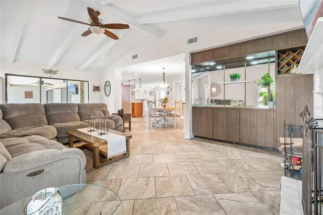 a living room with furniture and a dining table with chandelier