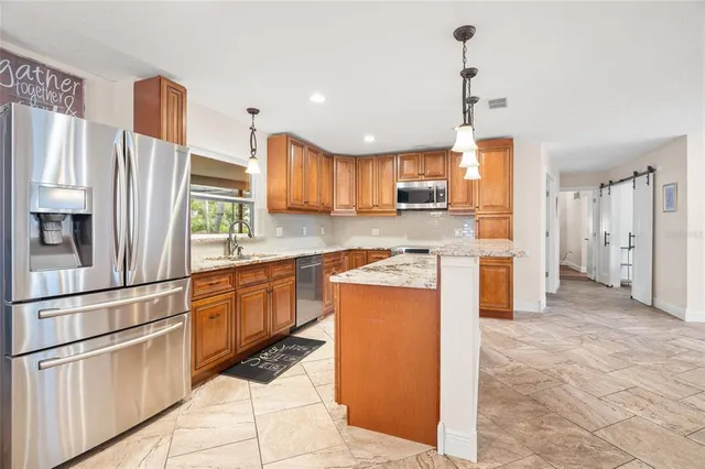 a kitchen with stainless steel appliances granite countertop a refrigerator a stove a sink and a refrigerator