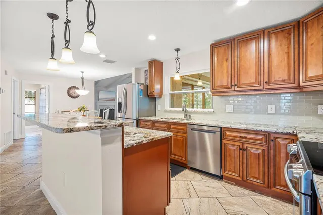 a kitchen with stainless steel appliances granite countertop a sink a stove and a wooden floors
