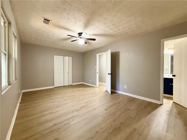 a view of an empty room with a window and wooden floor