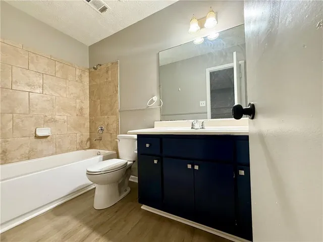 a bathroom with a double vanity sink a toilet a mirror and shower