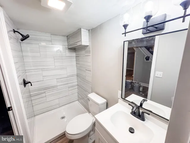 a bathroom with a sink a toilet a mirror and shower