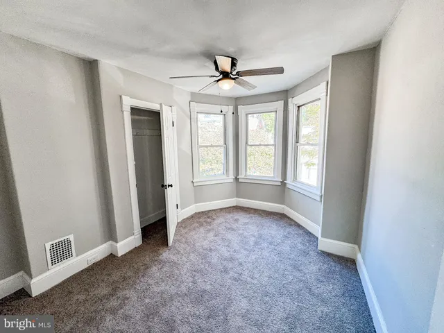 an empty room with windows and fan