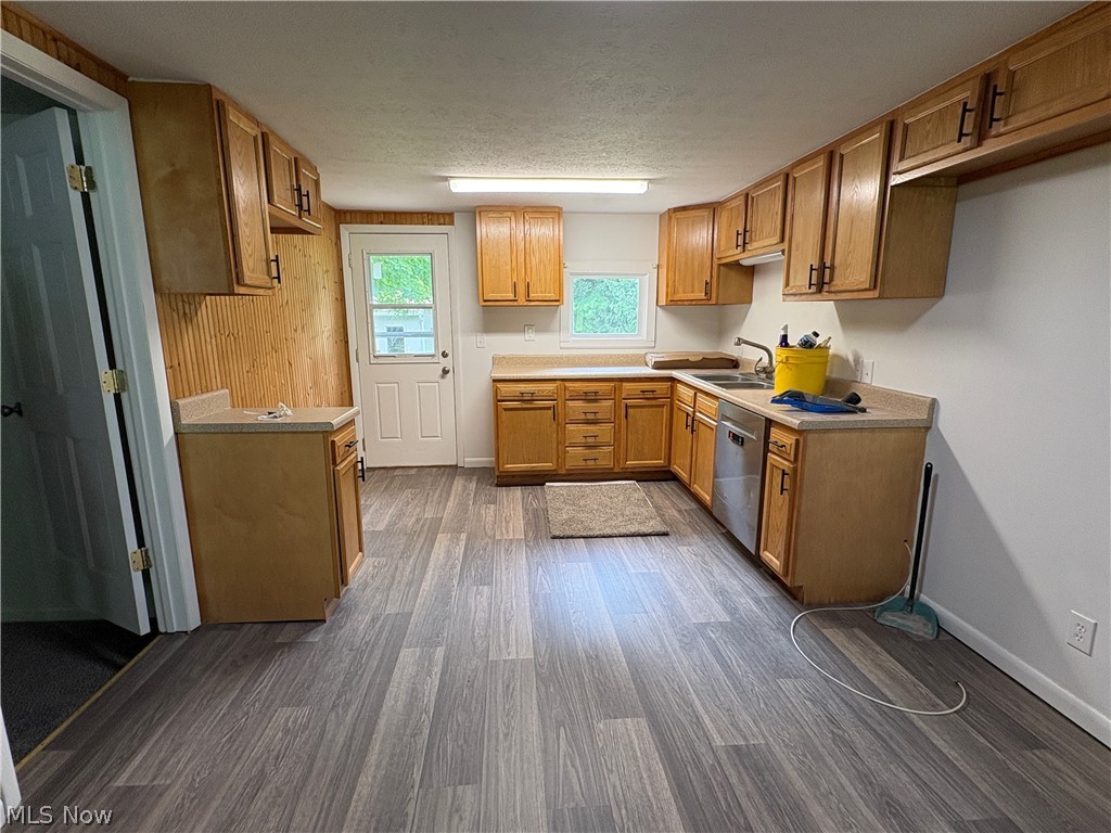 1448 Winding Road Parkersburg, WV 26104 - Photo 8 of 12 Expansive kitchen featuring wood-finish flooring, extensive wood cabinetry with dark hardware, light countertops, and a built-in stainless steel dishwasher