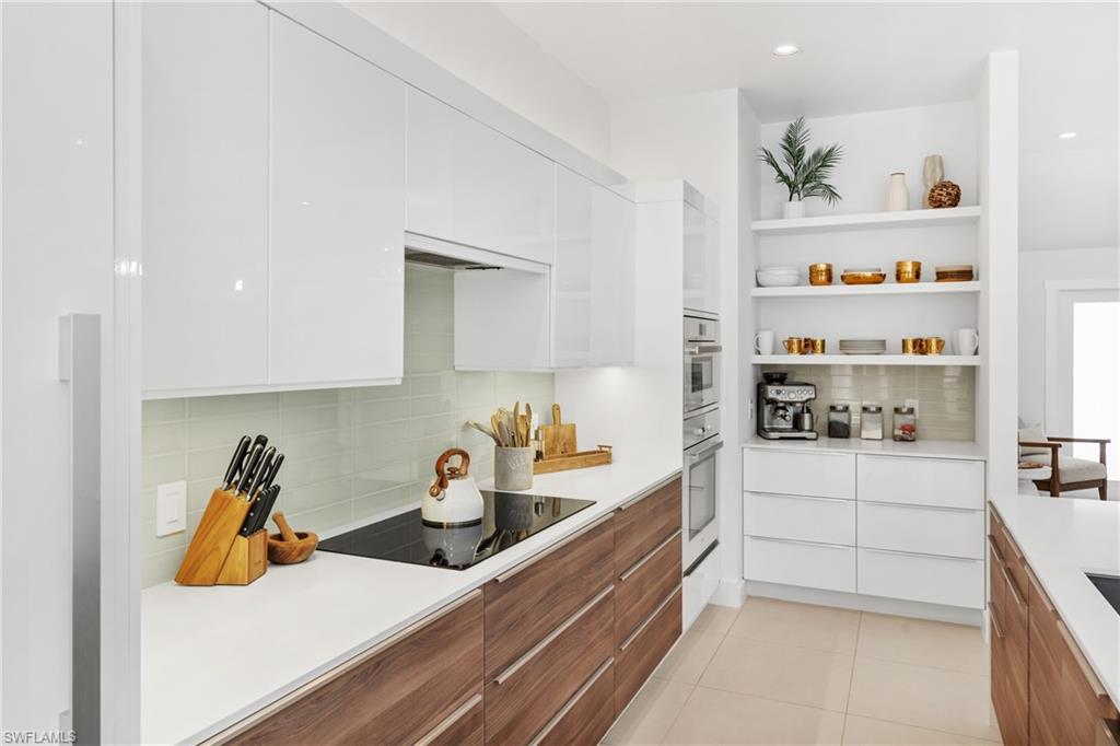 516 Neapolitan Lane Naples, FL 34103 - Photo 8 of 49 Kitchen featuring modern cabinets, white cabinetry, brown cabinets, open shelves, and tasteful backsplash