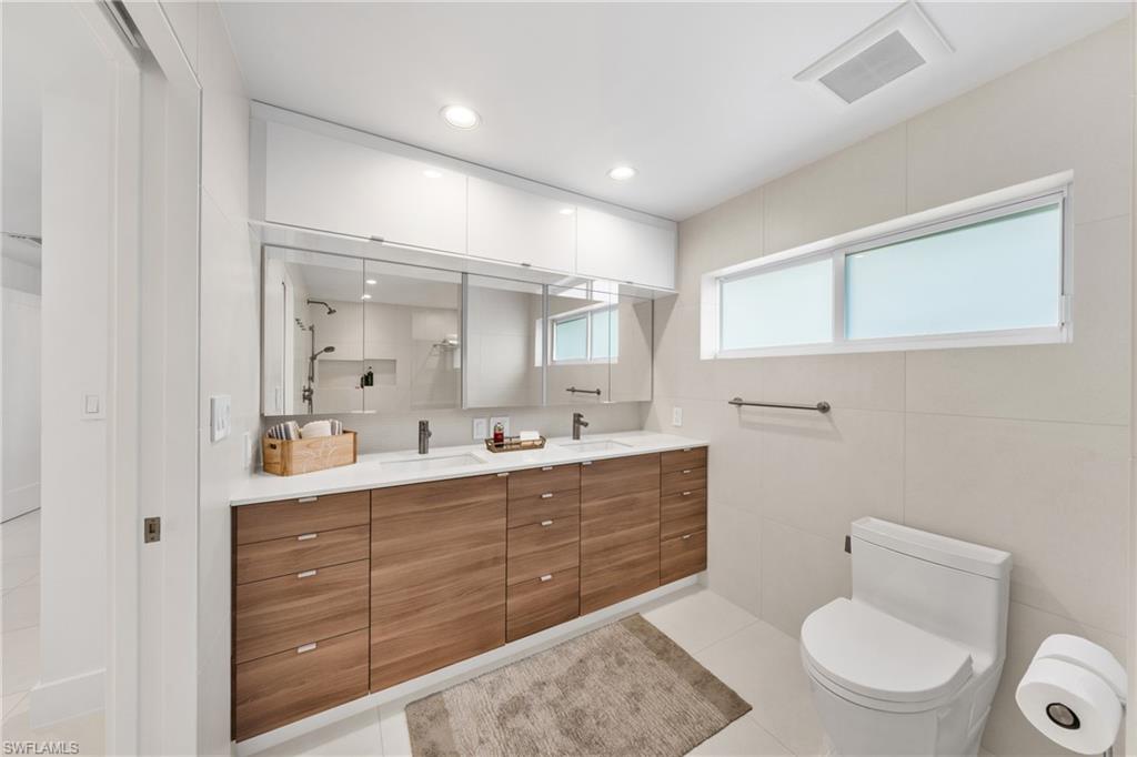 516 Neapolitan Lane Naples, FL 34103 - Photo 20 of 49 Full bath featuring double vanity, light tile patterned floors, a shower, recessed lighting, and tile walls