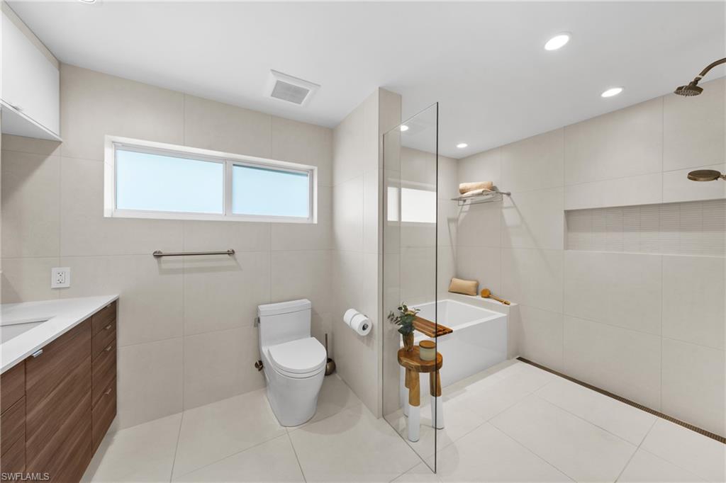 516 Neapolitan Lane Naples, FL 34103 - Photo 21 of 49 Bathroom with tile walls, a bathtub, light tile patterned floors, a walk in shower, and vanity