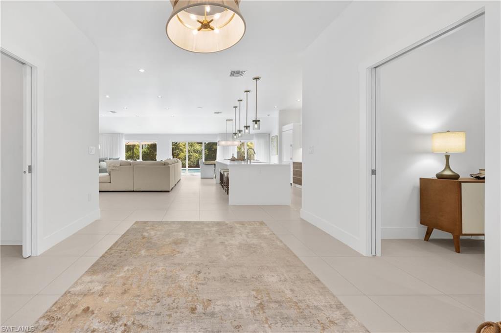 516 Neapolitan Lane Naples, FL 34103 - Photo 26 of 49 Hall with recessed lighting, light tile patterned floors, and a chandelier