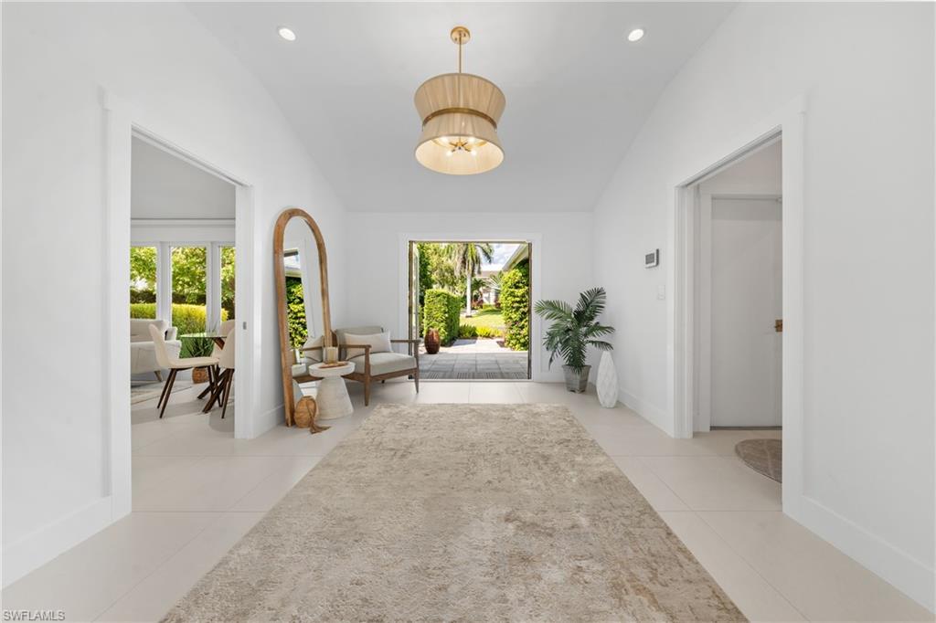 516 Neapolitan Lane Naples, FL 34103 - Photo 27 of 49 Foyer featuring recessed lighting, vaulted ceiling, plenty of natural light, light tile patterned floors, and a chandelier