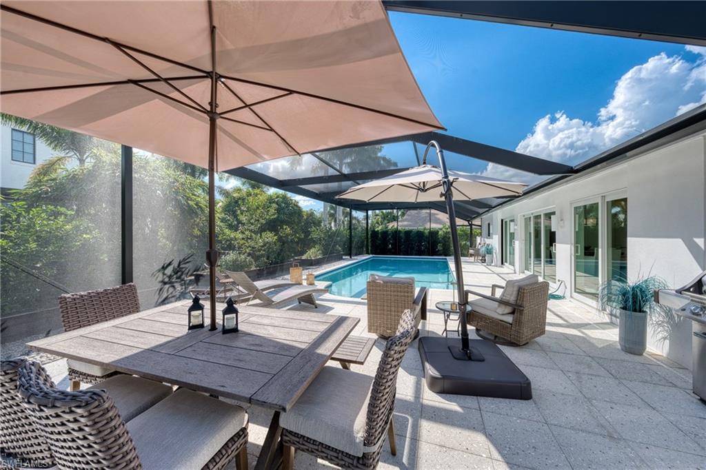 516 Neapolitan Lane Naples, FL 34103 - Photo 34 of 49 Outdoor pool featuring a sunroom, a patio area, outdoor dining area, and glass enclosure