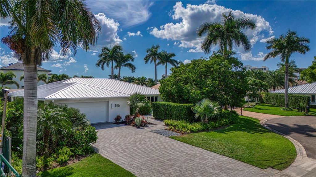 516 Neapolitan Lane Naples, FL 34103 - Photo 42 of 49 View of front facade with decorative driveway, an attached garage, a metal roof, a standing seam roof, and a front lawn