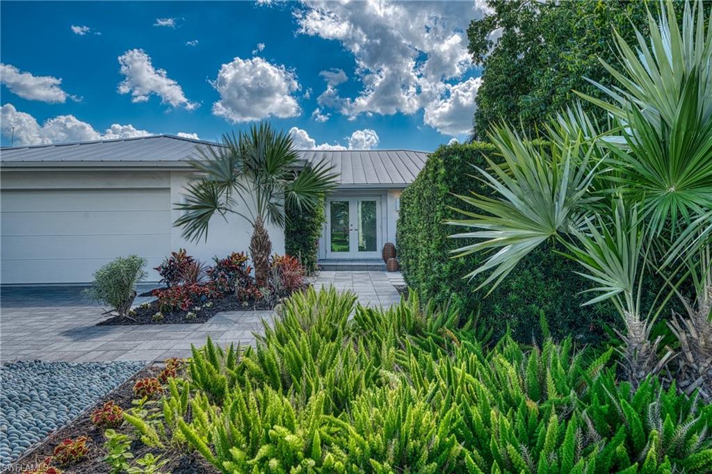 516 Neapolitan Lane Naples, FL 34103 - Photo 43 of 49 View of front of home with a garage, a metal roof, driveway, and french doors