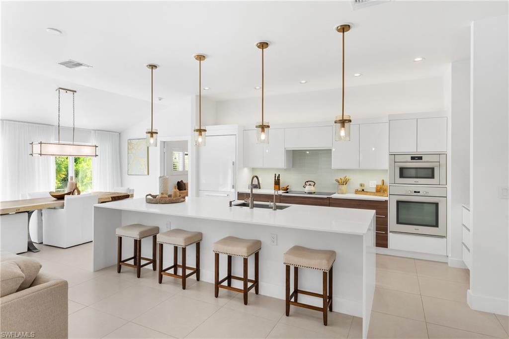 516 Neapolitan Lane Naples, FL 34103 - Photo 46 of 49 Kitchen with white cabinetry, open floor plan, a kitchen breakfast bar, a spacious island, and light tile patterned floors
