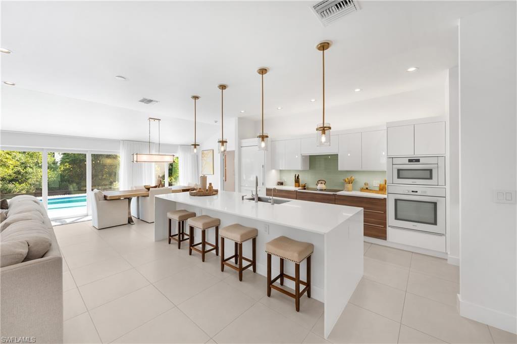 516 Neapolitan Lane Naples, FL 34103 - Photo 47 of 49 Kitchen with white cabinetry, open floor plan, a spacious island, modern cabinets, and a breakfast bar