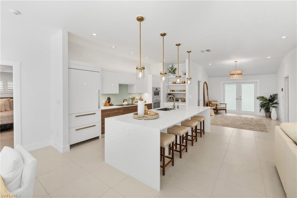 516 Neapolitan Lane Naples, FL 34103 - Photo 48 of 49 Kitchen with white cabinetry, modern cabinets, open floor plan, decorative light fixtures, and light tile patterned floors