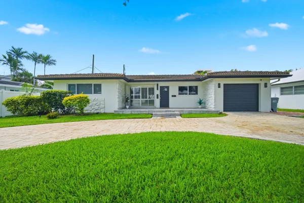 a front view of a house with a yard and potted plants