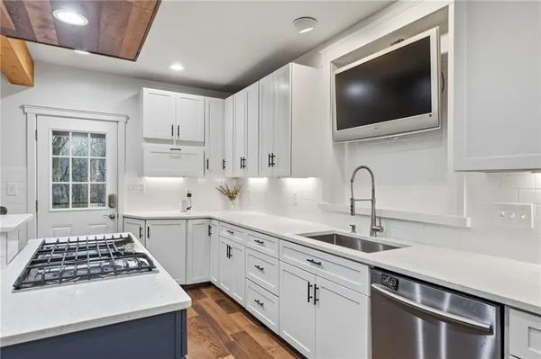 a kitchen with white cabinets a sink and a stove with wooden floor