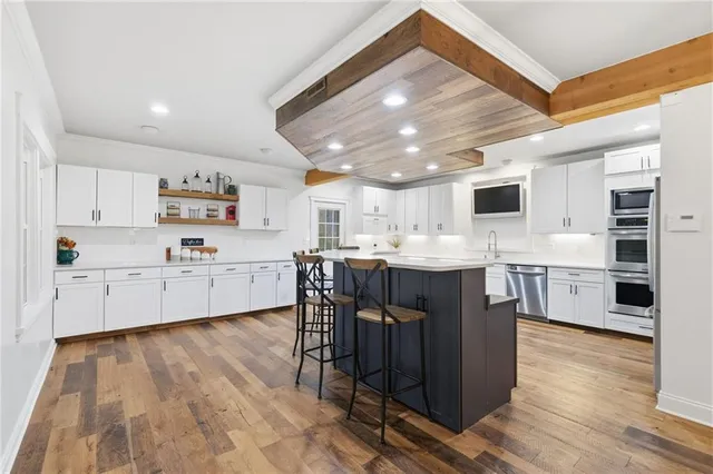 a kitchen with stainless steel appliances kitchen island granite countertop a sink cabinets and wooden floor