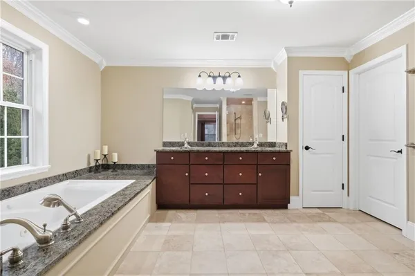 a spacious bathroom with a tub sink and mirror