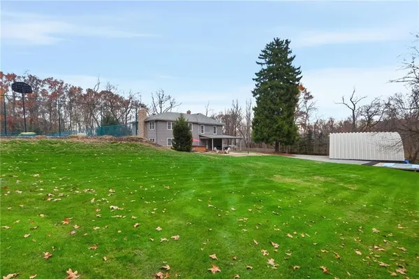 a view of a house with a big yard and large trees